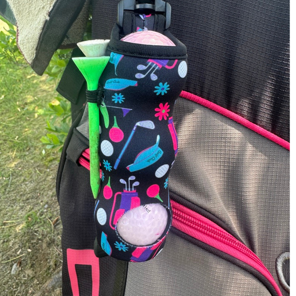 Colorful neoprene golf ball holder with clip and white golf ball on tan textured background
