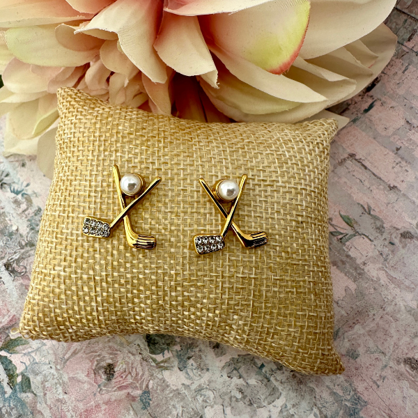 Golf pearl stud earrings with crossed club design and rhinestones on decorative cushion.