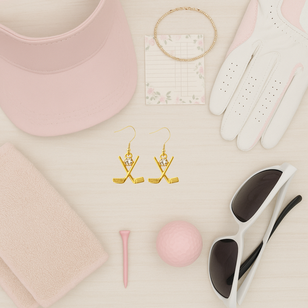 Gold golf earrings among golfing accessories like a cap, gloves, and ball, perfect for golf lovers.