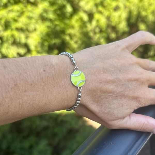Stylish tennis beaded bracelet with green enamel tennis ball charm on a hand, perfect tennis gift and accessory.