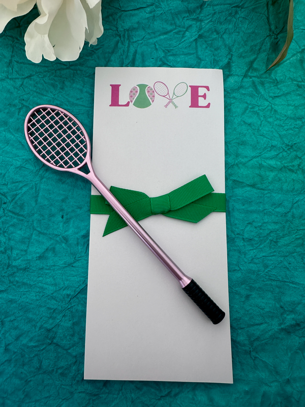 Tennis-themed notepad and pen set featuring a pink tennis racket pen on a decorative backdrop.